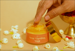 Hand taking a small amount of Deiveegaa Kesar Chandhan Tilak paste from the jar